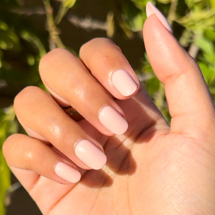 Pointe | Extra Short | Round - Tab Press-On soft ballerina pink false nails on hand in natural sunlight outdoors