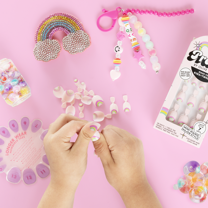 Rainbow Connection - Pressies | Extra Short Short | Round showing pastel pink press on nails with small rainbows on hands and packaging on pink background