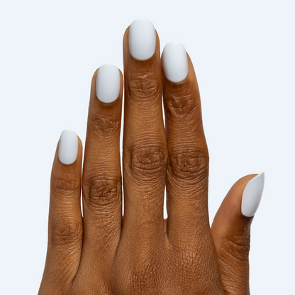 Rink | Short | Round - Tab Press-On matte white false nails on hand with smooth finish against pale background