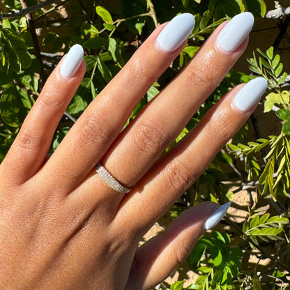 Rink | Short | Round - Tab Press-On glossy icy blue false nails on hand with silver ring outdoors by green foliage