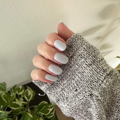 Rink | Short | Round - Tab Press-On glossy matte white press-on nails on hand wearing cozy knit sweater indoors with plant nearby