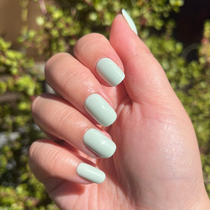 Seafoam | Short | Squoval - Tab Press-On pastel green press-on nails with smooth glossy finish in natural sunlight on hand