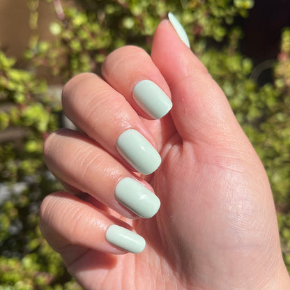 Seafoam | Short | Squoval - Tab Press-On pastel green press-on nails with smooth glossy finish in natural sunlight on hand