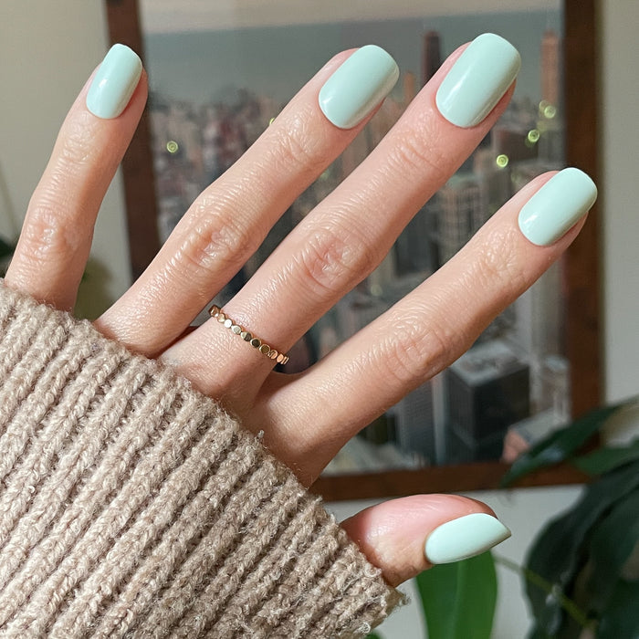 Seafoam | Short | Squoval - Tab Press-On pastel green press-on nails with smooth finish on hand wearing cozy knit sleeve