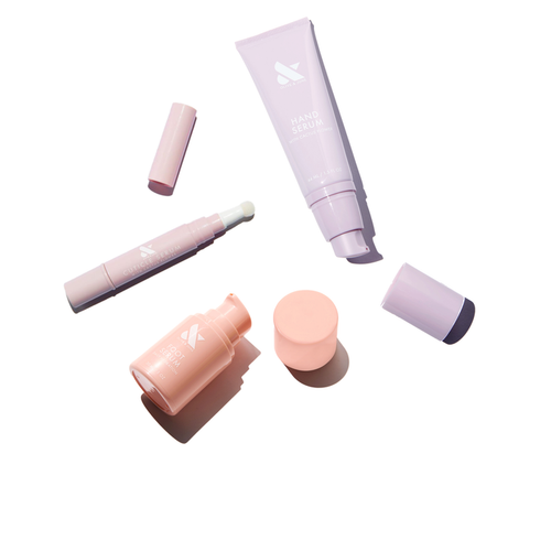 Signature Serum Set with hand serum, cuticle serum, and foot serum in pastel pink and lavender packaging on white background