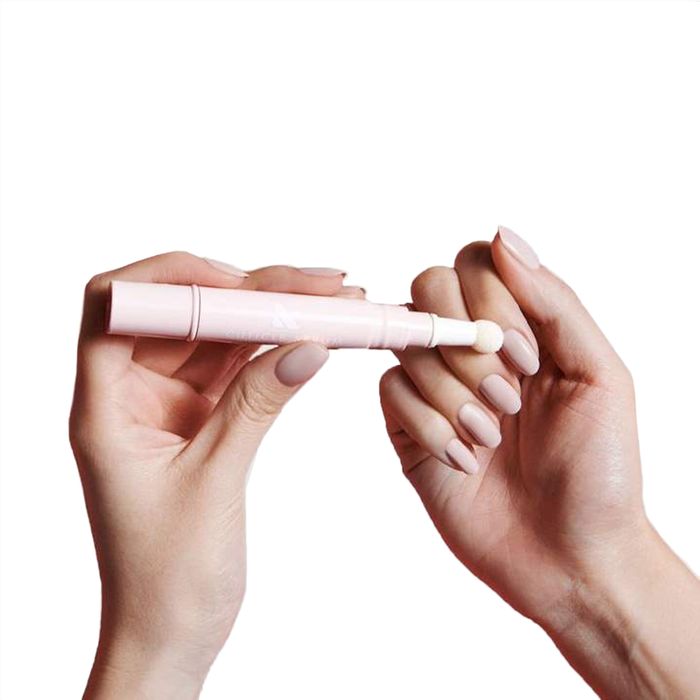 Hands holding and applying Signature Serum Set cuticle serum with soft pink applicator on pale nails