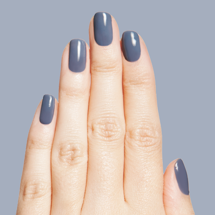 Fingers with nails painted in Slate - Gel, a smooth midtone slate blue gel polish on neutral background