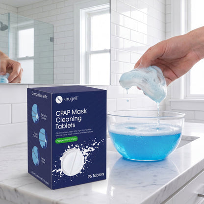Hand taking a mask out of a bowl next to a box of Snugell CPAP Mask cleaning tablets