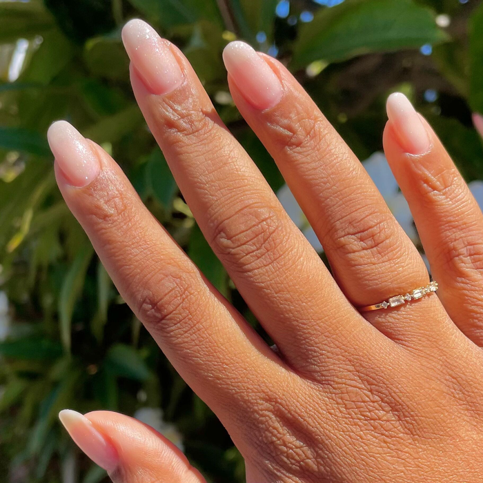 Soft Tint - Builder Gel on natural almond-shaped nails with sheer blush and fine silver sparkle manicure outdoors