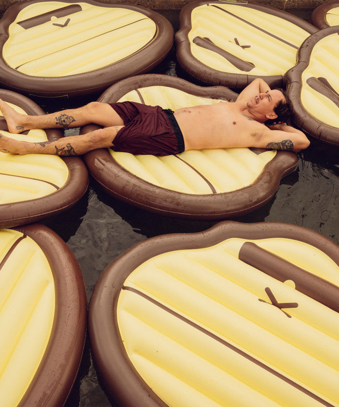 Man relaxing on multiple Sonny Pool Float water mattresses in a pool Sun Bum