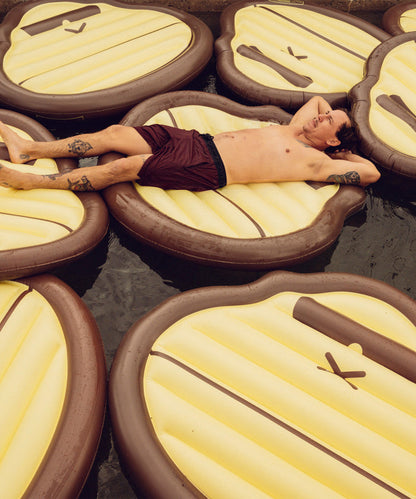 Man relaxing on multiple Sonny Pool Float water mattresses in a pool Sun Bum