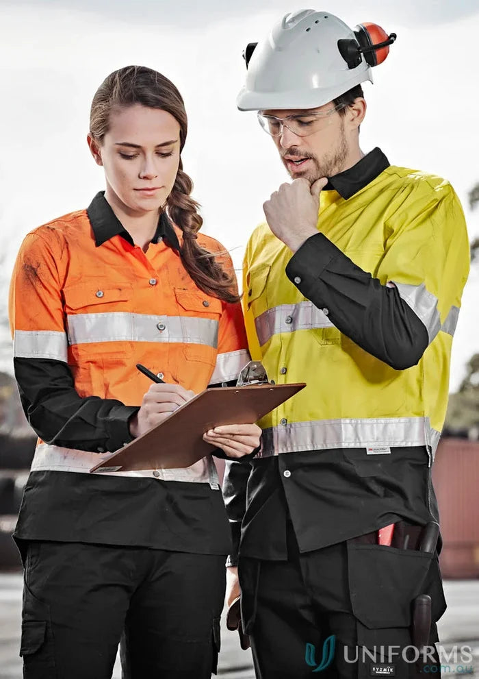 Two construction workers in safety gear wearing Syzmik Mens Industrial Long Sleeve Shirt hoop taped zw123 for demanding work environments