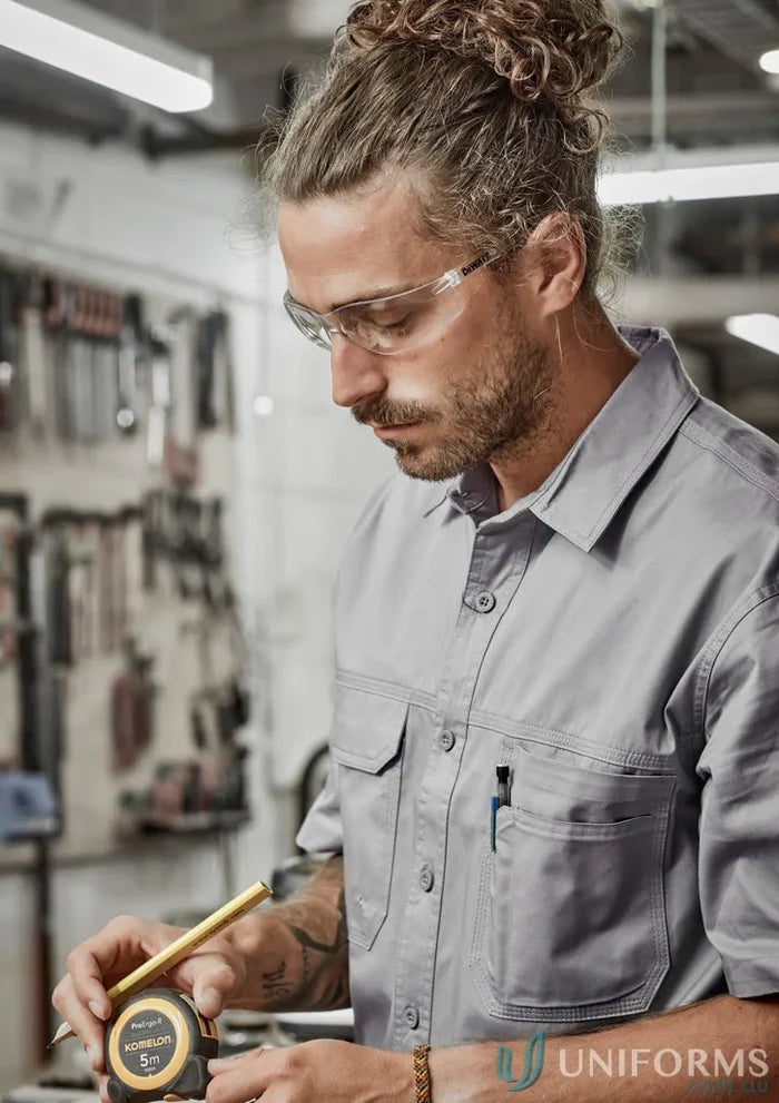 Man in safety glasses measuring with tape wearing Syzmik Mens Lightweight Tradie Short Sleeve Shirt zw120