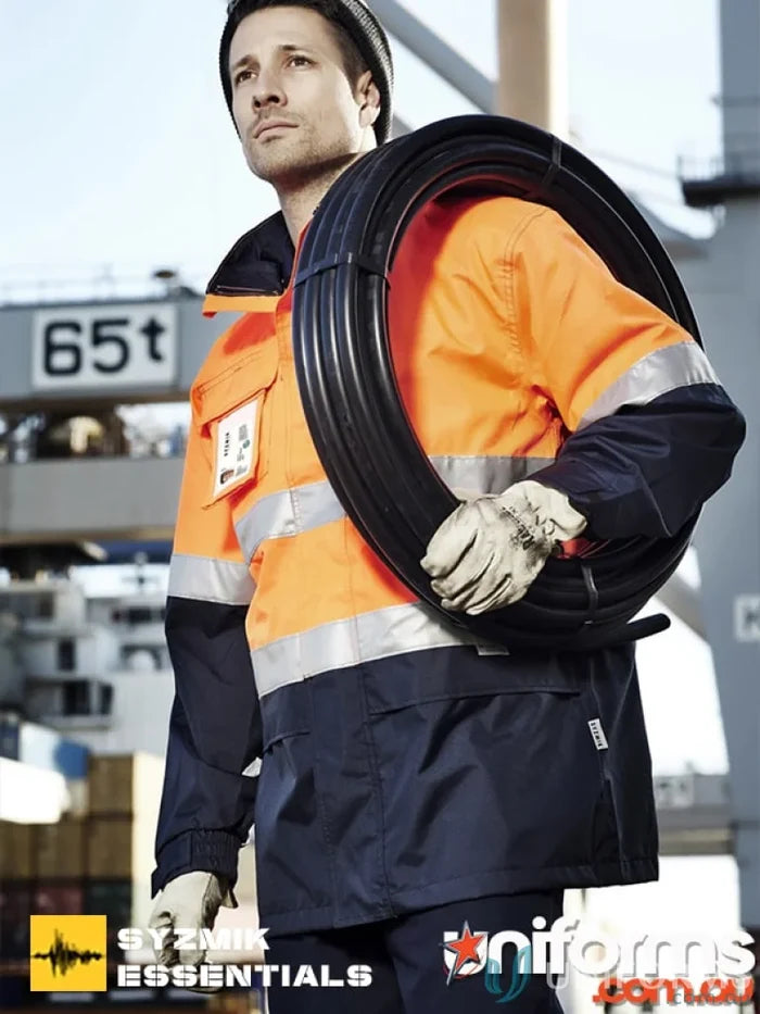Man in workwear carrying a coil wearing Syzmik Ultralight Waterproof Jacket for outdoor work