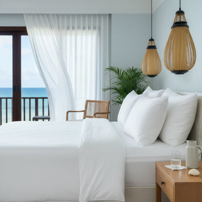 Bedroom with white bedding, wooden nightstand, and ocean view.