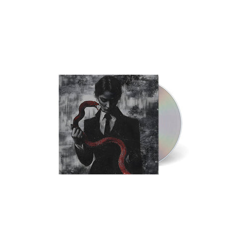 A CD case from TX2, featuring dark art of a suited figure holding a red snake on a textured grayscale background. The partially visible, reflective CD is perfect for fans of Ice Nine Kills or Johnny 3 Tears.