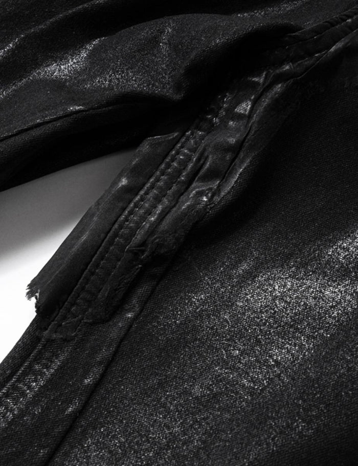 Rear view of black denim jeans highlighting patchwork design and waxed textured surface