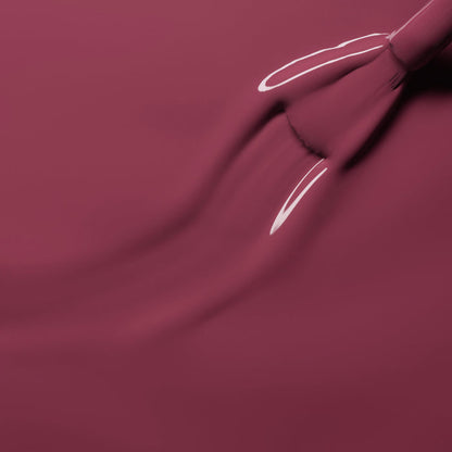 A close-up of a brush applying Manucurist's Victoria Plum nail polish, showing glossy streaks in the fresh, wet finish.