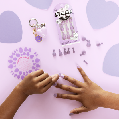 You're Invited - Pressies | Extra Short Short | Round showing hand with pastel purple press on manicure nails and nail size guide on lavender background